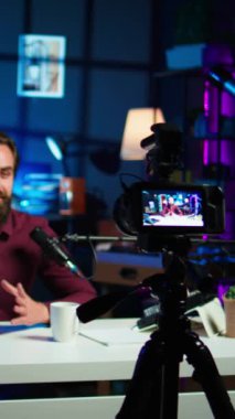 Dikey video içerik oluşturucu rgb lights stüdyosunda online şov sunuyor, profesyonel ekipman kullanarak vlog çekiyor. Kamerayla çekilen yayın sırasında bilgi sunan Vlog kaydedici