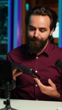 Stüdyodaki dikey videocu, marka sponsorluk videosundan dizüstü bilgisayarı onaylıyor, akıllı telefonuyla tripodla çekim yapıyor. Teknik uzman, not defterini tanıtarak, telefonla ve kamerayla kayıt yaparak pazarlamayı etkiliyor.