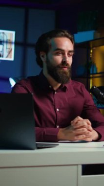 Dikey video Mutlu medya yıldızı tripoddaki akıllı telefonu kullanarak çevrimiçi yayın platformları için vlog kanal girişini filme alıyor. Neşeli adam izleyicileri selamlıyor, bugün video konusunu sunuyor, cep telefonuyla kayıt yapıyor