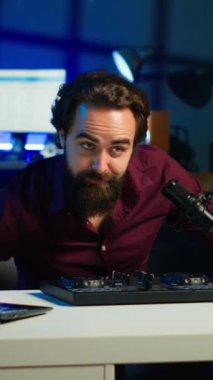 Dikey video sanatçısı DJ 'i filme alıyor, ses denetleyicisinden izleyicilere örnekler gösteriyor. Modern müzik ekipmanlarını ev stüdyosundaki abonelere gösteren viral internet yıldızı, kamera