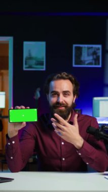 Dikey videolu neşeli adam akıllı telefon performansını değerlendiriyor, kullanılan yüksek kaliteli bileşenlerden memnun. Çevrimiçi kanal ve kamera için neşeli içerik oluşturucu cep telefonu incelemesi çekiyor