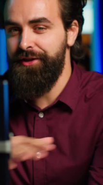 Stüdyodaki Happy 'nin dikey videosu seyirciyi selamlıyor, selfie çubuğunda akıllı telefon kullanarak canlı yayın yapıyor, kapatın. Q 'yu çeken adam ve cep telefonuyla bir oturum, cevap