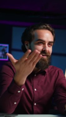 Stüdyodaki Happy 'nin dikey videosu seyirciyi selamlıyor, selfie çubuğunda akıllı telefon kullanarak canlı yayın yapıyor, kapatın. Q 'yu çeken adam ve cep telefonuyla bir oturum, cevap