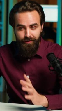 Dikey video ASMR sanatçısı stüdyoda tripodun üzerinde kaliteli mikrofon ve akıllı telefon kullanarak stres karşıtı videolar yapıyor, fısıldayan sesler çıkarıyor. Uyutma için mikrofon ve cep telefonu kullanan bir adam.
