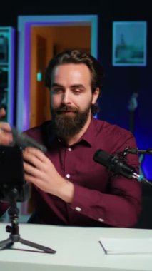 Dikey video teknolojisi gurusu V mount bataryasını sunuyor, cep telefonunu tripoda ve profesyonel mikrofona kullanarak teknoloji incelemesi yapıyor. Kafkas vlogger aygıt özelliklerini yükleme, kayıt