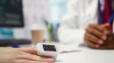 Doktor oksijen seviyelerini ve doygunluğunu ölçmek için hastaya oksimetre uyguluyor. Tesisteki muayenede hayati belirtileri kontrol ediyor. Sağlık sigortası için bir kadına danışmak. Kapatın. Kamera B.