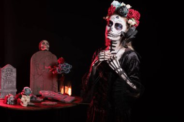 Dia de los Muertos partisine katılan siyah gül tutan kadın nesiller arasındaki kültürel gelenekleri koruyor. Meksika kültürünü kutlamak için Catrina kostümü giyen çiçekli ürkütücü kadın.