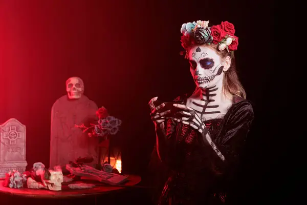 Stock image Woman playing videogames on handheld device during Day of the Dead Mexican event honoring dead loved ones. Person enjoying smartphone gaming during ancient Aztec custom of celebrating ancestors