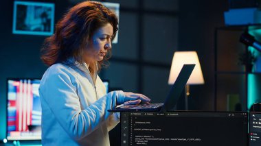 Bilgisayarı kullanarak yazılım hata ayıklama yapan geliştirici, kod satırlarındaki arızaları kontrol eden, hatalara kızan. Evinde dolaşan bir kadın defter aygıtı ve kamera A ile kodlama sorunlarını düzeltiyor.
