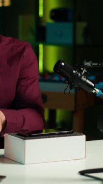 Neon lit stüdyosundaki dikey video Media yıldızı markalı sponsorluk videosundan cep telefonunu sunar, özellikleri analiz eder. Nüfuzlu kişi, sosyal medya hesabı takip eden teknoloji meraklılarının telefonlarını inceledi