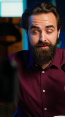 Ev stüdyosundaki üretim ekipmanlarıyla video kaydederken kendisi hakkında konuşan dikey video yıldızı geceleri RGB ışıklarıyla aydınlatılıyor. Profesyonel mikrofonla konuşan bir şovmen.