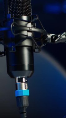 Çevrimiçi canlı yayın kanalı için internet şovu kaydetmek için kullanılan podcast mikrofonunun dikey görüntüsü. Ses yakalama ve kaydetme aracı boş oturma odasında neon ışıklı