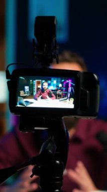 Dikey video içerik oluşturucu rgb lights stüdyosunda online şov sunuyor, profesyonel ekipman kullanarak vlog çekiyor. Kamerayla çekilen yayın sırasında bilgi sunan Vlog kaydedici