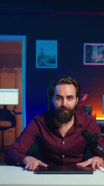 Stüdyodaki dikey video kaydedicisi marka sponsorluk videosundan dizüstü bilgisayarı onaylıyor, mikrofonla konuşuyor. İçerik oluşturucu, yüksek teknoloji mikrofonuyla kayıt yaparak, dizüstü bilgisayarın tanıtımını yapıyor.