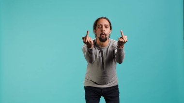 Irked man fighting with friend, doing middle finger sign gesturing, isolated over studio background. Outraged person arguing during conversation, doing obscene hand gestures, camera A clipart