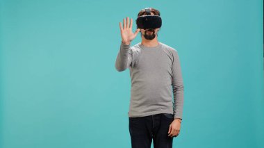Teknoloji meraklısı sanal gerçeklik gözlüğü takıyor, jestler yapıyor. Arap adam ileri teknoloji modern VR gözlükleri kullanıyor, dokunaklı hareketler yapıyor, stüdyo arka planı, kamera A