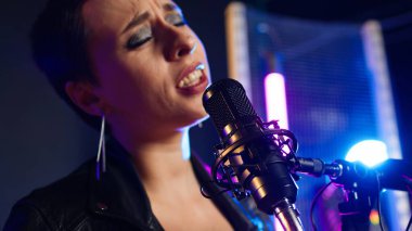 Fierce rock singer performs live singing into the microphone with passion. Cool edgy artist with rebellious energy creating a wild iconic performance in the heavy metal music industry. Camera A. clipart