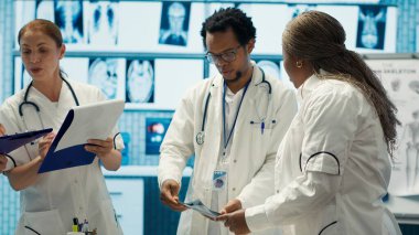Özel bir klinikte teşhis verilerini analiz eden ve tedaviyi planlayan bir grup sağlık çalışanı, işbirliğini vurguladı. Son test sonuçlarından sonra kurtarma planlarını koordine ediyorum. Kamera A.