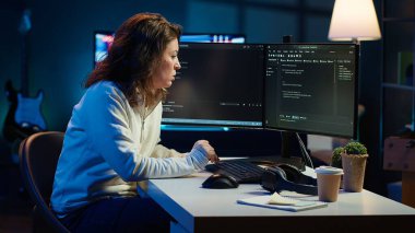 Masaüstü bilgisayarı kullanarak JavaScript programlama dilinde ev geliştirme yazılımı üzerinde çalışan bilişim uzmanı. Oturma odasındaki sistem mühendisi bilgisayardaki kod satırlarını klavye, kamera A kullanarak yazıyor.