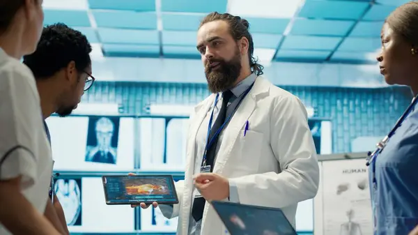 stock image Doctors meet to discuss healthcare records and x ray scans results at treatment center. Licensed medics focus on tests for disease prevention, demonstrating teamwork and expertise. Camera A.