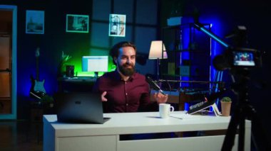 Neşeli içerik yaratıcısı rgb lights stüdyosunda online şov sunuyor profesyonel mikrofon kullanarak vlog çekiyor. Neşeli vlogger sunucu sunum sırasında yayın servis yayını, kamera B