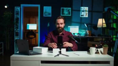 Neon lit stüdyosundaki medya yıldızı, markalı sponsorluk videosundan cep telefonunu sunuyor, özellikleri analiz ediyor. Nüfuzlu kişi, sosyal medya hesabı B 'yi takiben teknoloji meraklılarının telefonlarını inceledi.