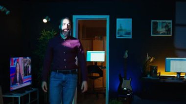 İçerik yaratıcısı, video bloguna başlamadan önce stüdyoda profesyonel mikrofonu ayarlıyor, selfie kamerasıyla kayıt yapıyor. Neon ışıklı ev stüdyosu hazırlayan, akıllı telefonlu çekim yapan, B kameralı adam.