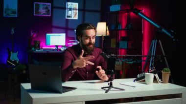 Stüdyoda tripoda bağlı akıllı telefon ve yüksek kaliteli mikrofon konuşmaları izleyicilerle tartışıyor. Sosyal medya videosu ve kamera B 'yi kaydetmek için cep telefonu ve profesyonel ekipman kullanan adam.