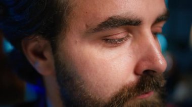 İçerik üreticisi, kendi hakkında konuşurken, gece RGB ışıklarıyla aydınlatılmış ev stüdyo içindeki üretim teçhizatıyla video kaydediyor. Profesyonel mikrofonla konuşan şovmen, kamera B