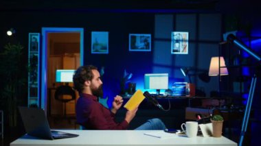 Stüdyoda yayınevinden yeni çıkan ciltli kitabı eleştiren neşeli bir internet yıldızı. Kitabın tanıtımını yapan ve aboneler için yazarın yeni romanını okuyan neşeli bir adam.