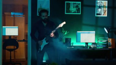 Video çekerken stüdyoda gitar çalan oyuncu bir internet yıldızı. Ana stüdyoda profesyonel mikrofonla video bloğu çekerken müzik aleti çalan enerjik içerik yaratıcısı, kamera A