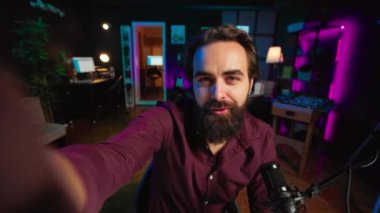 Neşeli konuşmacı profesyonel kayıt ekipmanlarıyla vlog kanalı girişini kaydediyor, abonelerle konuşuyor. Farklı konuları kapsayan, kendini selamlayan hayranlarını kaydeden iyimser video görüntüsü.