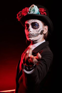 Bayan, Dia de los Muertos bayramında dini törenler için çok cezbedici bir davet veriyor. Kadın tahrik edici hareketler yapıyor, iskelet makyajı yapıyor, merhuma olan saygısını simgeliyor.