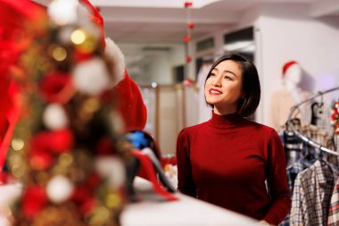 Noel Baba, mağazada çalışan ve Noel ruhunu kırmızı kostümle yayan müşterilere kıyafet gösteriyor. Asyalı kadın, erkeklerden eşya almak için yardım istiyor..