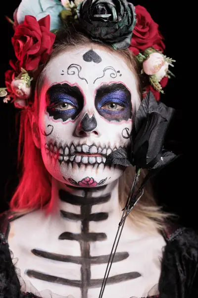 stock image Headshot portrait of woman holding rose during Day of the Dead Mexican celebration honoring dead loved ones. Person doing ancient Aztec custom of celebrating ancestors, holding black flower, close up