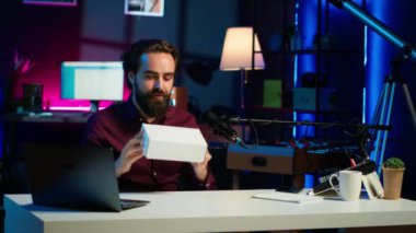 İçerik yaratıcı abonelerden gizemli bir kutu alıyor, paketlenmiş ürünleri boks yaparken çekmeye hazır. İnternet yıldızı sürpriz pakete işaret ediyor. Ev stüdyosunda kayıt yapıyor. Kamera A.
