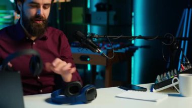 Teknik uzman kulaklıkları test ediyor, çevrimiçi yayın platformları için gözden geçiriyor. Profesyonel sesli sunucu internet şovu, ses karıştırıcı kullanarak ses duyarlılığını kontrol ediyor, kamera A