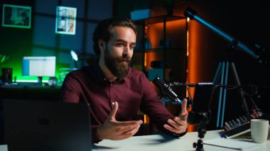 Medya yıldızı stüdyoda tripod dengeleyicisine bağlı akıllı telefondan izleyicilerle konuşuyor. Adam sosyal medya ve kamera B için oturma odasında video kaydetmek için cep telefonu kullanıyor.