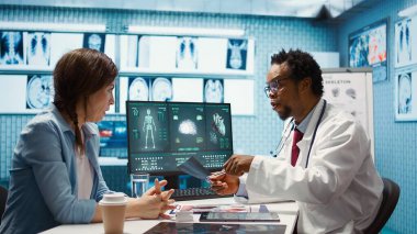 Tıbbi uzman teşhis için röntgen görüntülemesini açıklıyor, muayene sırasında tarama yorumu yapıyor. Profesyonel doktor bayan müşteriye geri bildirim yapar. Kamera B.