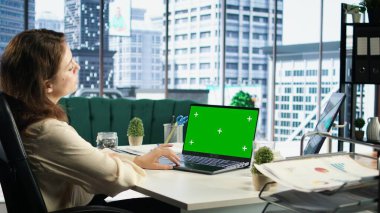 İşletme müdürü yeşil ekranla kendi ofisinde çalışıyor. Cihaz ekranına bakıyor ve yeni bir proje fikri geliştiriyor. Şirket kültürüyle güçlendirilmiş kadın girişimci. Kamera A.