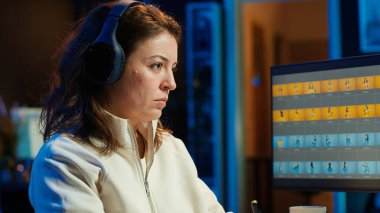 Fotoğraf editörü resim ışıklandırmasını düzenlemek için grafik tablet kullanıyor, görsel olarak çekici son ürünü dağıtıyor, podcastleri dinliyor. Freelancer ses kulaklığı takıyor, fotoğraflara bakıyor, kamera A