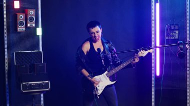 Grunge sinirli kız gece kulübünde bas gitarla şarkı söylüyor. Müzik performansına alternatif bir hava katıyor. Vahşi enerjisini gösteren harika bir müzisyen. Kamera B.