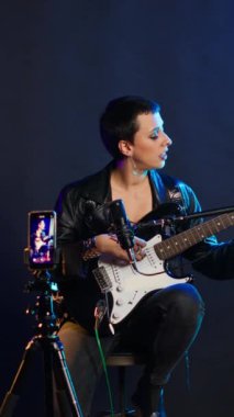 Dikey video şarkı söyleme koçu stüdyoda ses eğitimi için çevrimiçi bir ders kaydediyor. Canlı yayın özel dersler için ses egzersizleri. Heavy metal çalan bir müzik hocası temel şeyleri öğretiyor. Kamera B.
