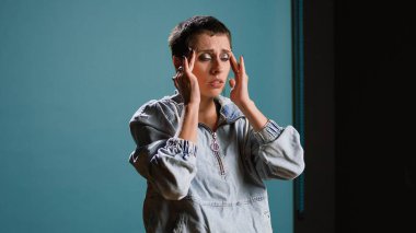 Stüdyoda acı veren bir baş ağrısından muzdarip bir model, şakaklarını ovuyor ve rahatsızlığı konusunda hayal kırıklığına uğruyor. Migren ağrısı olan genç ve şık bir kadın. Kamera A.