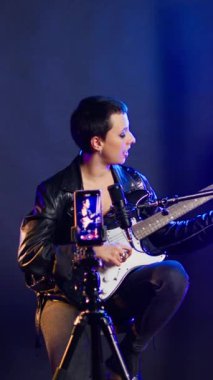 Dikey video ses eğitimi eğitmeni insanlara online derste gitar çalmayı öğretiyor, sanal derste pratik yapıyor. Süperstar vokal koçu şan dersleri alıyor.