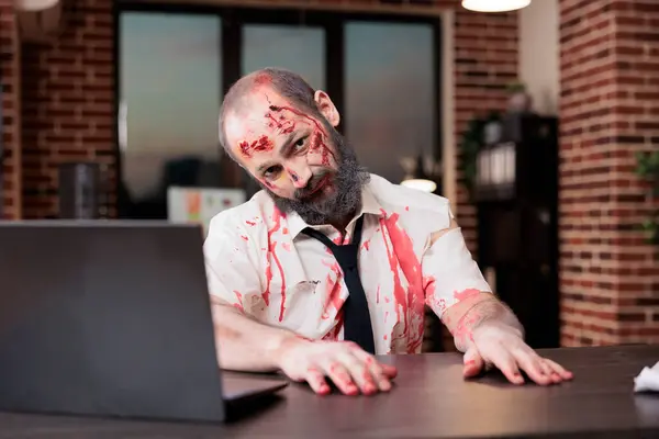 stock image Portrait of overworked professional with weary expression, feeling burnout at office desk, looking like zombie. Businessman covered in bruises, looking exhausted after working too much