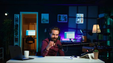 Çocuksu adam video çekmek için mikrofon kullanarak Vlog 'a yaratıcı giriş yapıyor. Ana stüdyoda mikrofon ve kamera B ile video kayıt kanalı için çekimler yaparken, enerji içeriği yaratıcısı sandalyede dönüyor