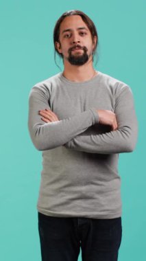 Gülümseyen, mutlu görünen, mavi stüdyo arka planında izole edilmiş neşeli bir Arap 'ın dikey videosu. Mutlu anlamlı insan şık giyinmiş sırıtıyor, tatmin olmuş hissediyor, kamera A.