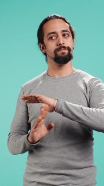 İddialı bir adamın zaman isteyen, el hareketleri yapan, yorgun hisseden iddialı bir adamın dikey video portresi. Mutsuz kişi öfkeli duraklama işareti yapıyor, ara vermek istiyor, stüdyo arka planı, kamera B
