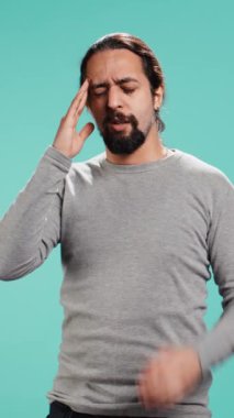 Aşırı çalışmaktan, baş ağrısından, stüdyo arka planında izole edilmekten yorgun düşmüş bir adamın dikey video portresi. Yorgun insan yorgunluk, stüdyo arkaplanı, kamera B